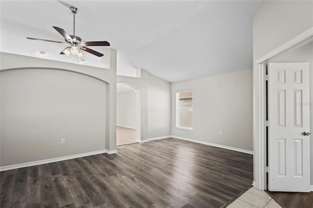 empty room featuring dark wood-type flooring, ceiling fan, vaulted ceiling, and a textured ceiling