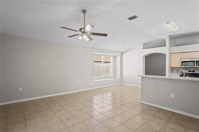 unfurnished living room featuring vaulted ceiling, light tile patterned floors, and ceiling fan