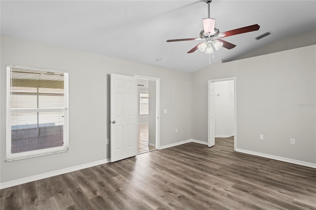 empty room featuring lofted ceiling, a healthy amount of sunlight, and dark hardwood / wood-style flooring