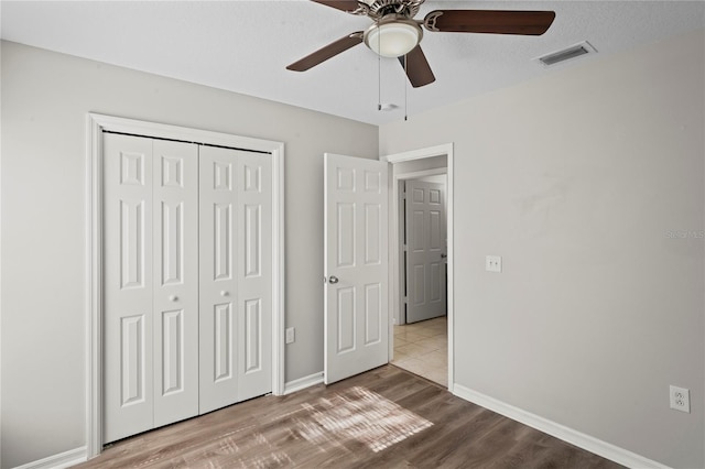 unfurnished bedroom featuring a textured ceiling, light hardwood / wood-style floors, a closet, and ceiling fan