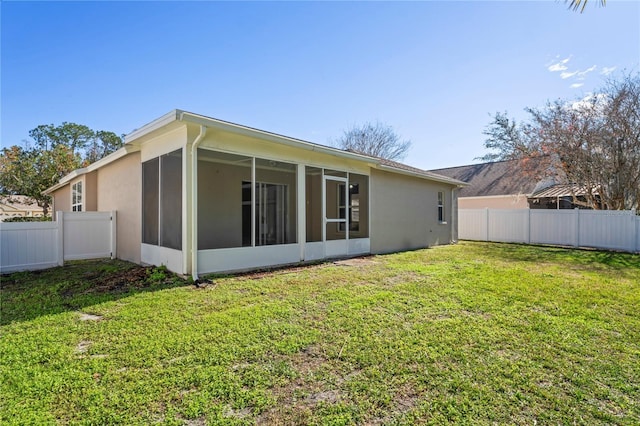 back of property with a sunroom and a lawn