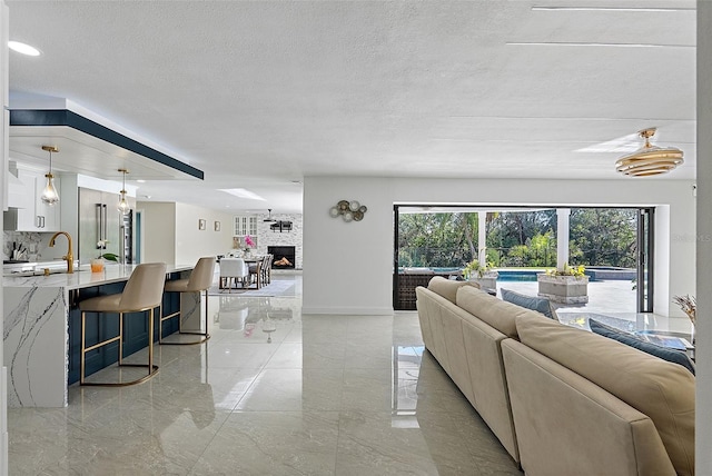 living room featuring a fireplace, sink, and a textured ceiling