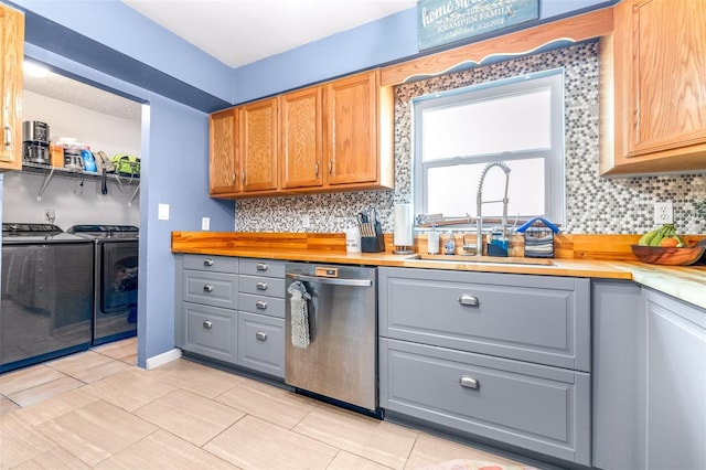 kitchen featuring gray cabinets, dishwasher, washer and clothes dryer, and a sink