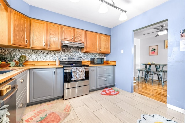 kitchen featuring tasteful backsplash, appliances with stainless steel finishes, gray cabinetry, under cabinet range hood, and wooden counters