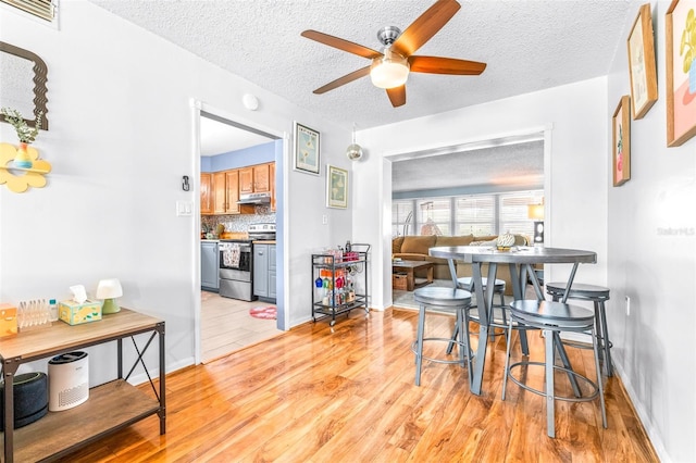 dining space with visible vents, a textured ceiling, light wood-style flooring, and a ceiling fan