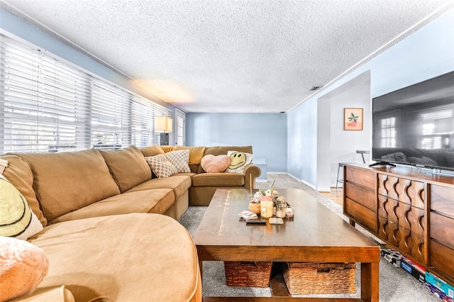 living area with a textured ceiling, visible vents, a wealth of natural light, and baseboards