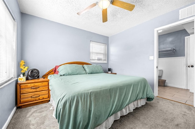 bedroom featuring a textured ceiling, multiple windows, visible vents, and light colored carpet