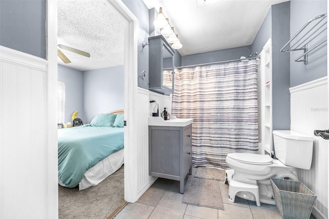 ensuite bathroom featuring a textured ceiling, tile patterned flooring, connected bathroom, toilet, and vanity