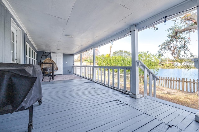 wooden terrace with a grill, a water view, and fence