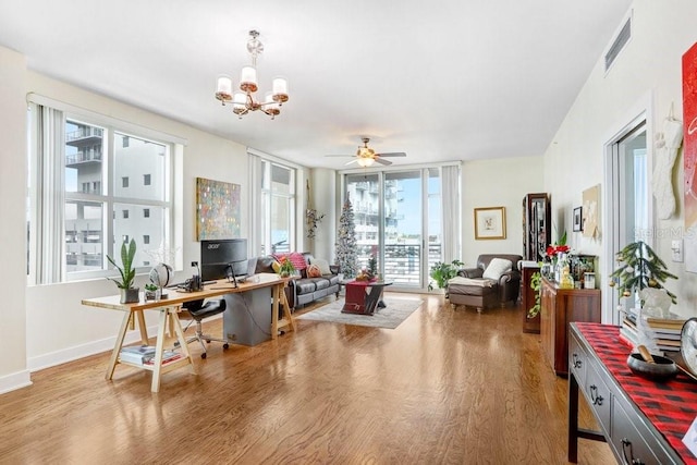 interior space with ceiling fan with notable chandelier, plenty of natural light, and wood-type flooring