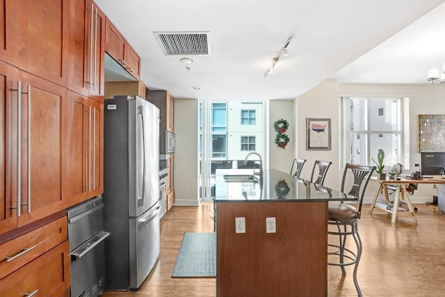 kitchen featuring sink, a kitchen breakfast bar, an island with sink, stainless steel appliances, and light hardwood / wood-style floors