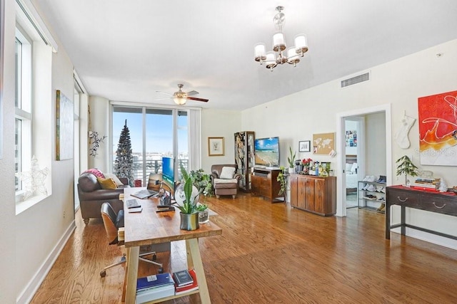 office featuring hardwood / wood-style floors, ceiling fan with notable chandelier, and a wall of windows