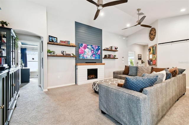 carpeted living room with vaulted ceiling, a large fireplace, and ceiling fan