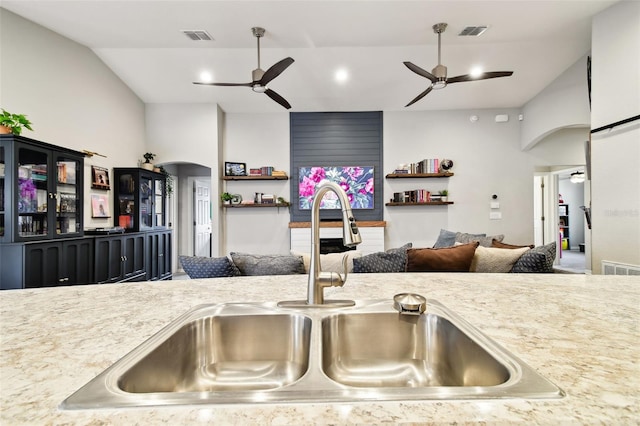 kitchen featuring light stone counters, ceiling fan, and sink