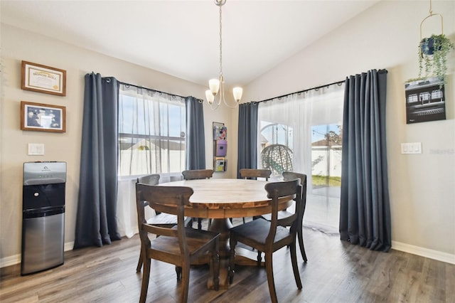 dining space featuring wood-type flooring, a chandelier, and vaulted ceiling