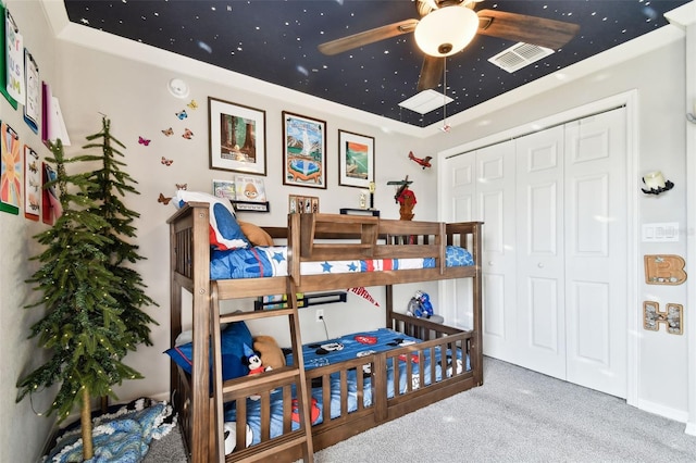 carpeted bedroom with ornamental molding, ceiling fan, and a closet