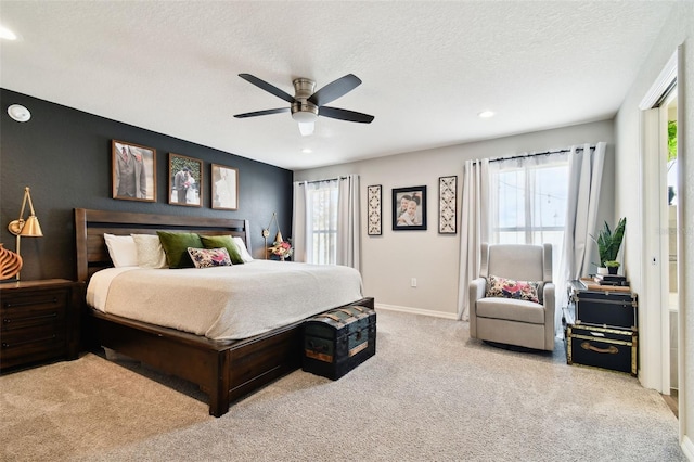 bedroom featuring multiple windows, light carpet, a textured ceiling, and ceiling fan