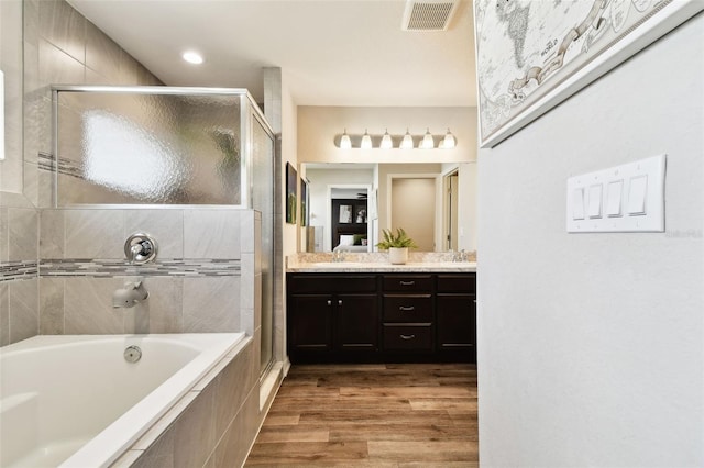 bathroom featuring vanity, hardwood / wood-style flooring, and plus walk in shower