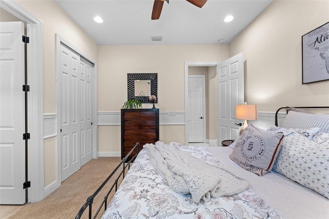 bedroom featuring light colored carpet, ceiling fan, and a closet