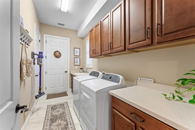 laundry room with sink, a textured ceiling, cabinets, and washing machine and clothes dryer