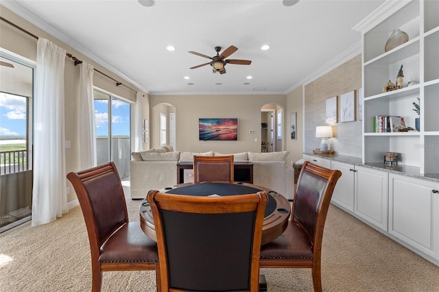 dining space featuring a healthy amount of sunlight, light colored carpet, ornamental molding, and ceiling fan