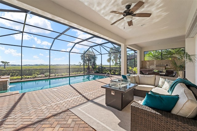 view of swimming pool with a lanai, a patio area, an outdoor living space with a fire pit, and ceiling fan