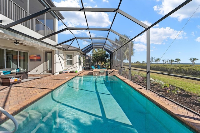 view of pool with an in ground hot tub, ceiling fan, glass enclosure, and a patio