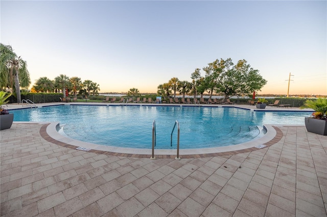 pool at dusk with a patio area