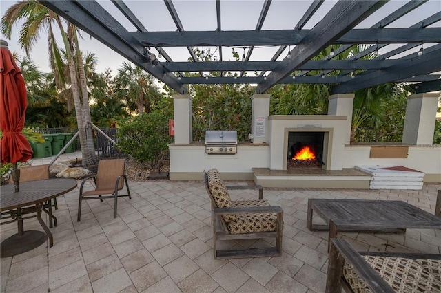 view of patio with area for grilling, exterior fireplace, and a pergola