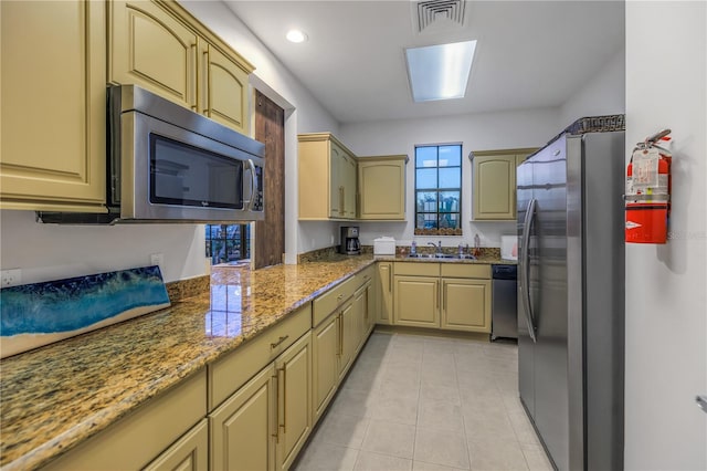 kitchen with light stone counters, sink, light tile patterned floors, and appliances with stainless steel finishes