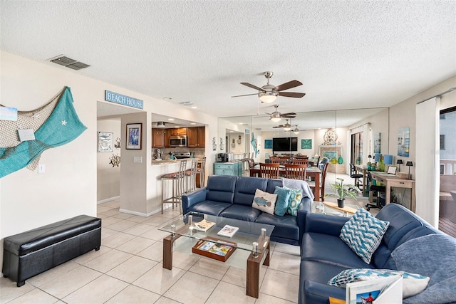 living room with ceiling fan, a textured ceiling, and light tile patterned floors