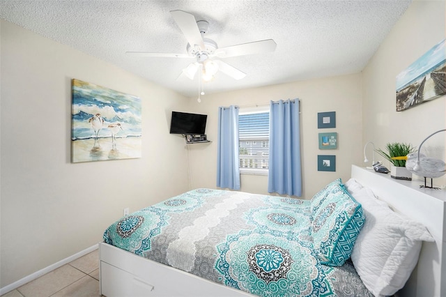 bedroom featuring light tile patterned flooring, ceiling fan, and a textured ceiling