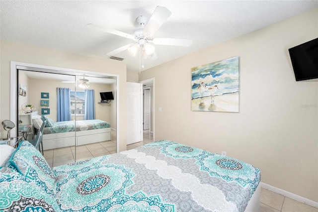 bedroom with light tile patterned flooring, ceiling fan, a closet, and a textured ceiling