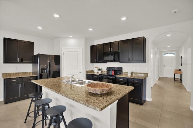 kitchen featuring sink, black appliances, an island with sink, and a breakfast bar