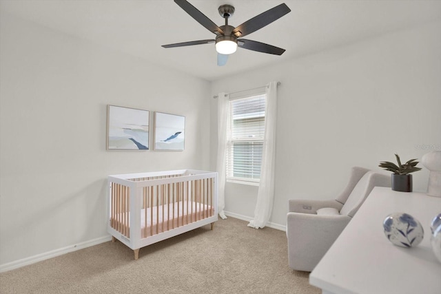 carpeted bedroom featuring a crib and ceiling fan