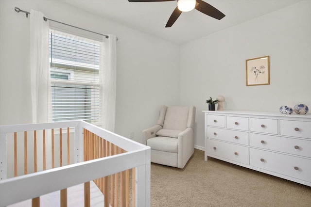 bedroom with light carpet, a nursery area, and ceiling fan