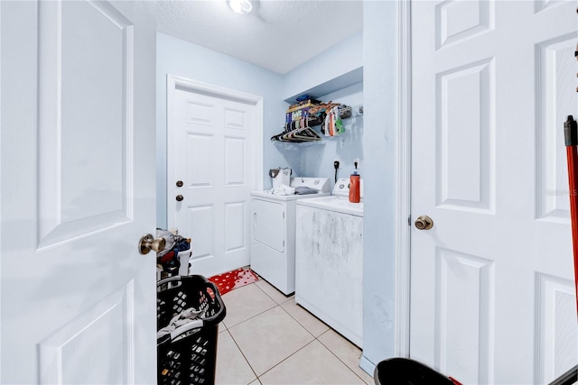 laundry area with light tile patterned floors, washing machine and clothes dryer, and a textured ceiling