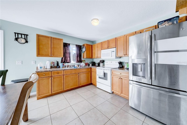 kitchen with light tile patterned flooring, light stone countertops, and white appliances