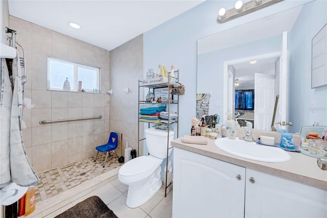 bathroom featuring tiled shower, vanity, toilet, and tile patterned flooring