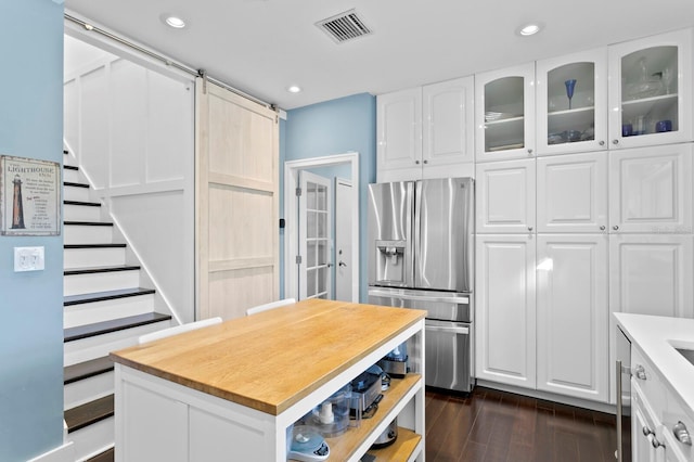 kitchen with dark hardwood / wood-style floors, white cabinetry, stainless steel fridge, a center island, and a barn door