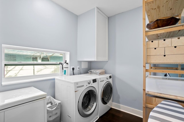 clothes washing area featuring cabinets, washing machine and clothes dryer, and dark hardwood / wood-style floors