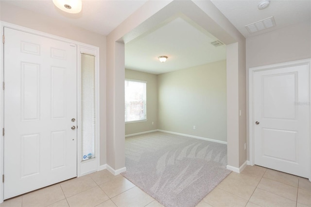 foyer entrance with light carpet, light tile patterned flooring, visible vents, and baseboards