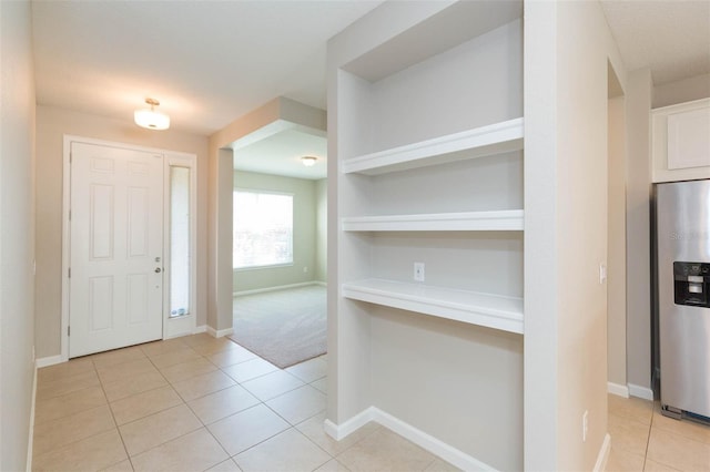 foyer featuring baseboards and light tile patterned floors