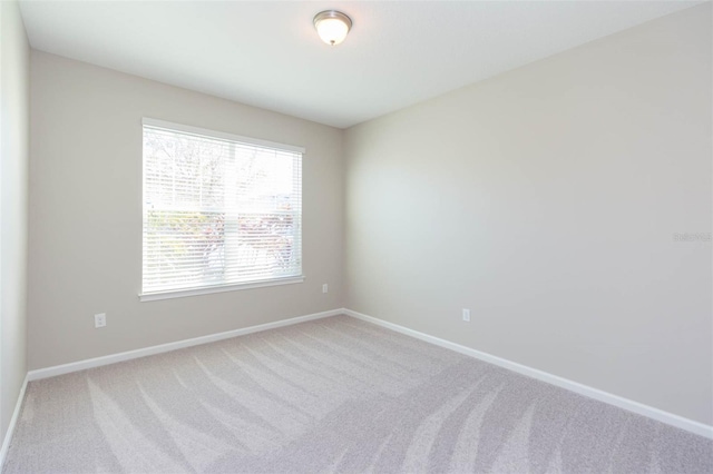 carpeted empty room featuring baseboards