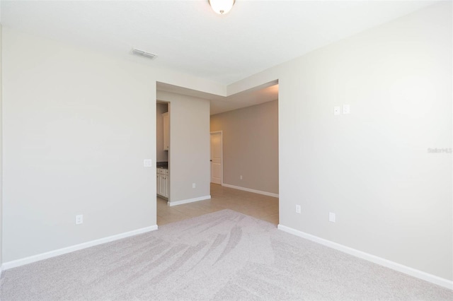 unfurnished room featuring light colored carpet, visible vents, and baseboards