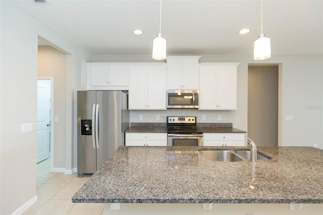 kitchen with dark stone counters, appliances with stainless steel finishes, white cabinetry, pendant lighting, and a sink