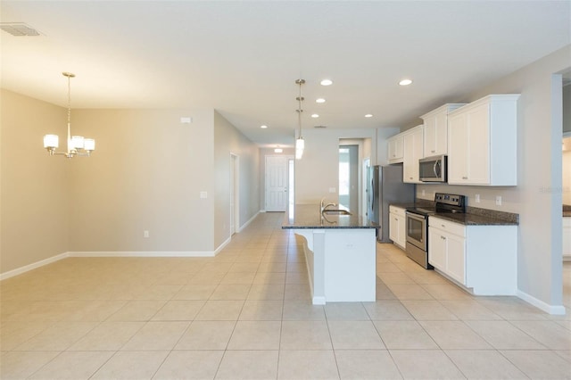 kitchen with light tile patterned floors, appliances with stainless steel finishes, hanging light fixtures, a kitchen island with sink, and white cabinetry