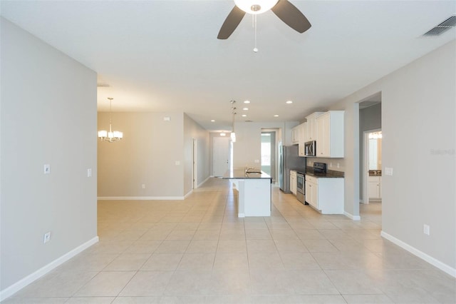 kitchen featuring a center island with sink, dark countertops, hanging light fixtures, appliances with stainless steel finishes, and white cabinetry