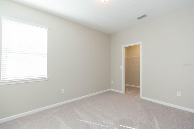 spare room with baseboards, visible vents, and light colored carpet