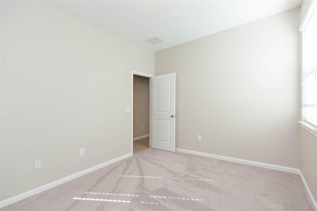 unfurnished room with light colored carpet, visible vents, and baseboards